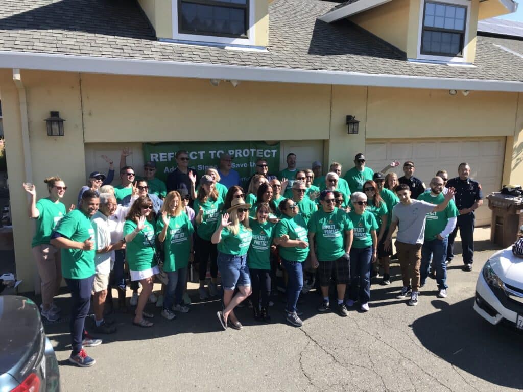 volunteer group standing in front of a Reflect to Protect banner
