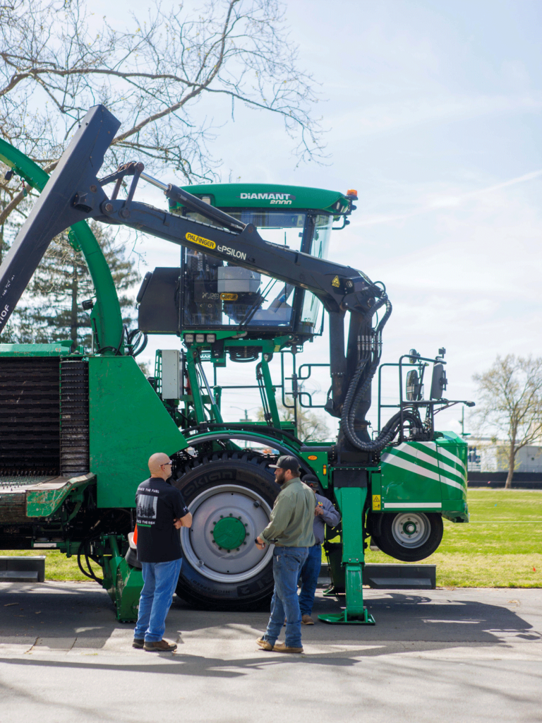 two men talking looking at a large piece of equipment 